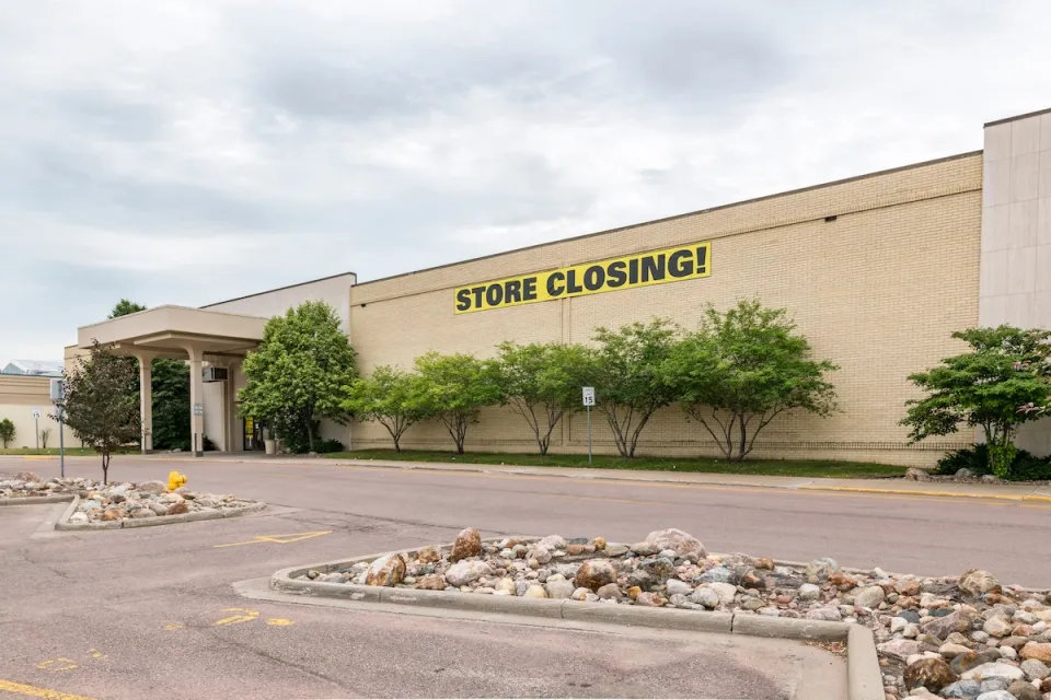 Large store in mall with yellow and black STORE CLOSING sign on front.